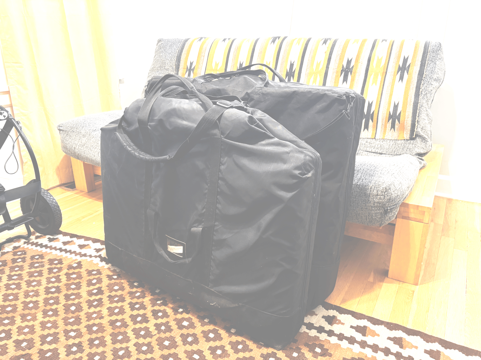 two massage tables folded in carrying bags, one notably larger than the other